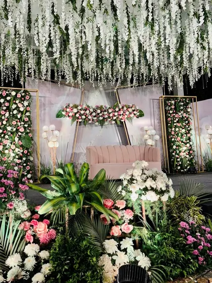 A beautiful reception backdrop with a ceiling of hanging white flowers and modern geometric frames filled with pink and white florals.