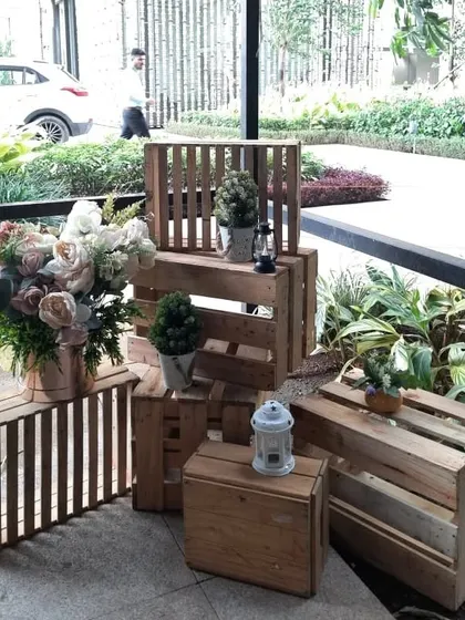 Rustic wooden crates and lanterns are used as decorative elements to add a charming and warm touch to the entrance of the dinner party.