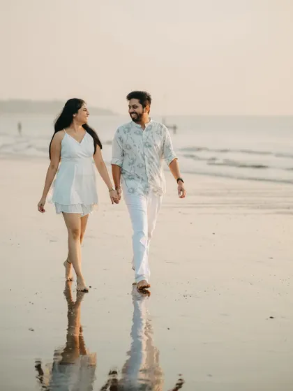 Walking hand-in-hand into our forever. A classic, romantic pre-wedding photograph on the beach as the sun sets, capturing the simple joy of being with the one you love.