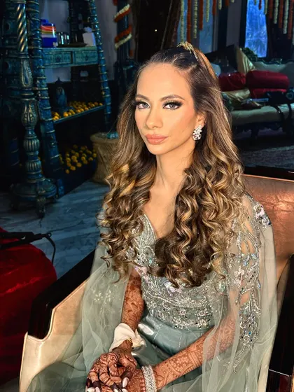 Sangeet ready in a stunning pastel green outfit. The makeup is glamorous, with a defined eye and a modern, curly ponytail.