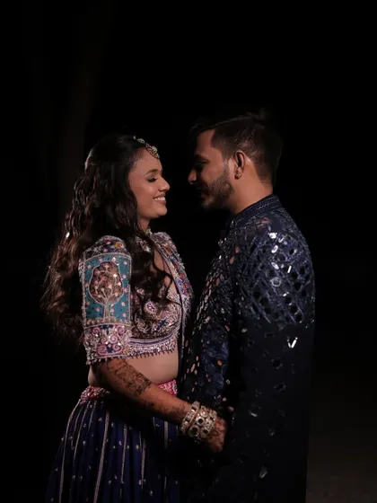 An intimate moment between the couple, their faces lit against the dark background.