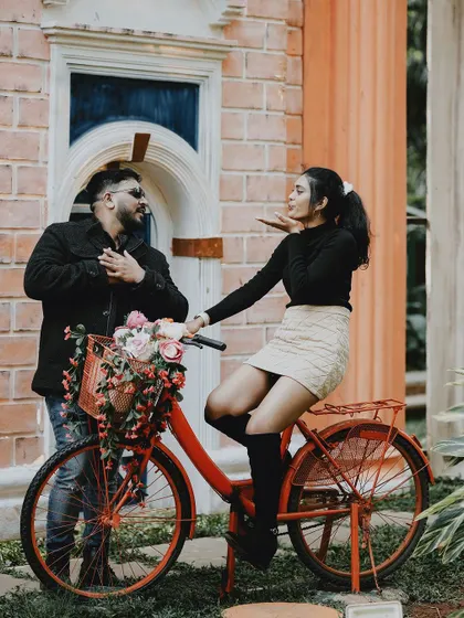 A fun and romantic pose with a flower-adorned red bicycle, capturing a sweet, vintage-inspired moment.
