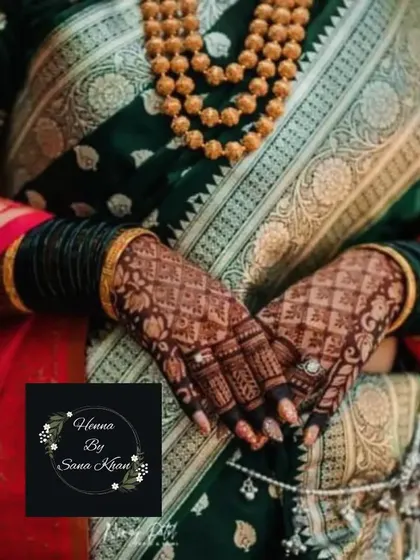 A beautiful shot of a bride's hands, showcasing a traditional check and floral design that perfectly complements her sari and jewelry.