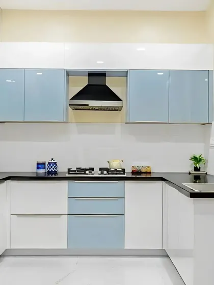 This U-shaped kitchen design is bright and airy, using a combination of white and light blue glossy cabinets. The black countertop provides a sharp contrast, and the layout is optimized for easy movement and access to all essentials.