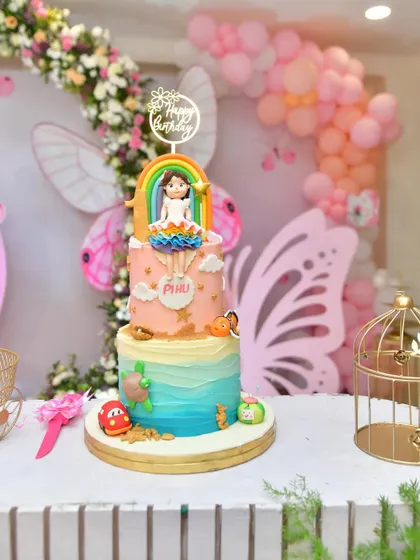 A fun and colorful custom cake for a party, featuring a rainbow and other playful elements.