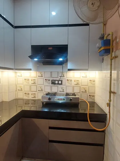 Even a small kitchen can be highly functional and attractive. This compact L-shaped kitchen features modern cabinets, a chimney, and under-cabinet lighting.