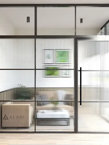 This view from outside the private office highlights the use of fluted glass partitions to maintain privacy while allowing natural light to flow through the space.