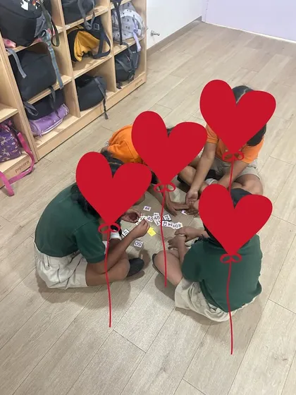 Young students sitting on the floor, deeply engaged in a card game. Floor-based activities can create a more relaxed and collaborative learning environment.