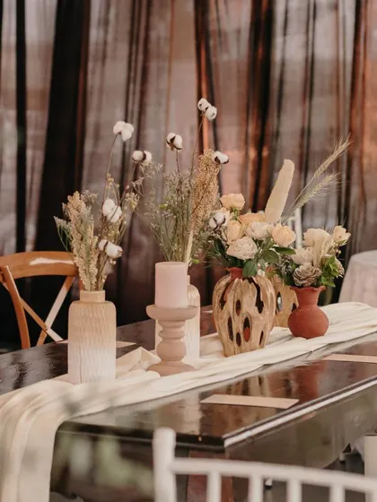 A table runner decorated with dried cotton stems and other rustic florals.
