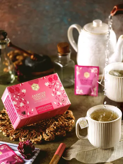A product shot of Mittal Teas' Jasmine Ginger tea, styled with a clean, bright aesthetic. The action of pouring water into the cup adds a dynamic element while keeping the focus firmly on the product.