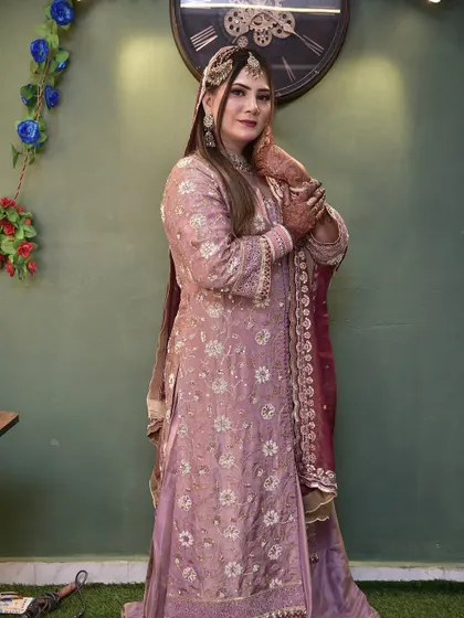 A full-length view of the bride in her stunning lavender sharara. Her hair is kept open and styled to complement the flowy silhouette of her outfit.