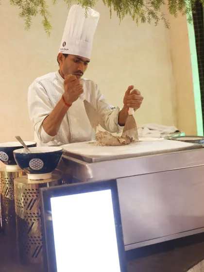 A chef prepares fresh ice cream rolls on a cold stone. This live dessert station is not only delicious but also provides a captivating visual spectacle for guests to enjoy.