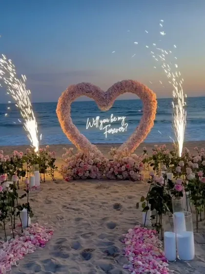 This is what a promise of forever looks like. I designed this dreamy beachside proposal with a custom floral heart arch, a neon sign, and perfectly timed pyrotechnics to create a truly unforgettable moment against the sunset.