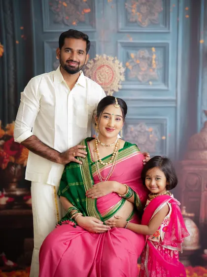 A beautiful family portrait celebrating tradition. The family is dressed in gorgeous ethnic wear, with big sister proudly standing by her mother's side.