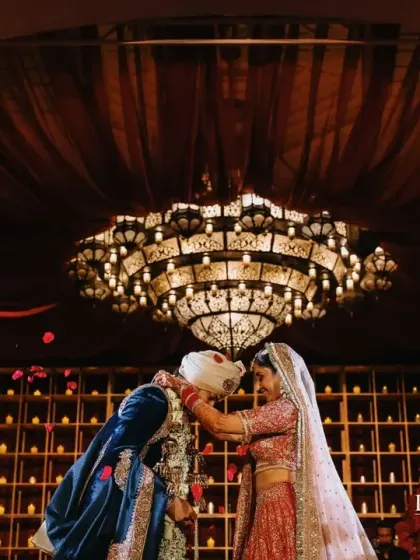 A beautiful varmala moment under a magnificent chandelier. The decor, with its wall of candles and rich red florals, created a portrait of floral elegance for this destination wedding in Bahrain.