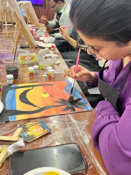 A close-up of a painter working on a sunset canvas. The details and color blending are coming along beautifully.