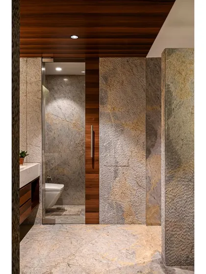 The bathroom design uses a continuous flow of honed marble on the floor and scratch-finish marble on the walls, creating a cave-like, sanctuary feel.
