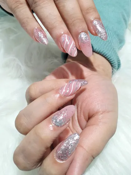 A side view of the pink and silver striped manicure, showing off the length of the extensions and the combination of glitter and line work.