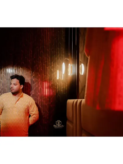A creative shot of the groom during his Haldi ceremony, using warm, dramatic lighting to create an artistic and memorable portrait.