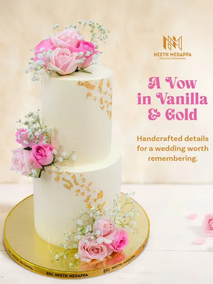A vow in vanilla and gold. This simple yet stunning two-tiered wedding cake is adorned with fresh pink roses, baby's breath, and delicate flecks of edible gold leaf.
