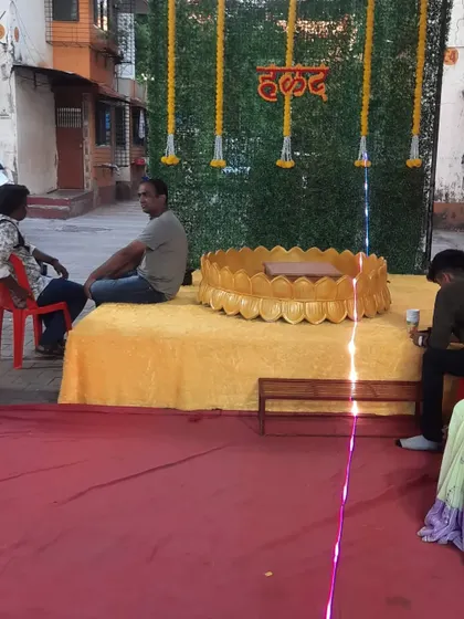 A simple yet functional Haldi stage with a green grass-like backdrop and a traditional baithak for the ceremony.