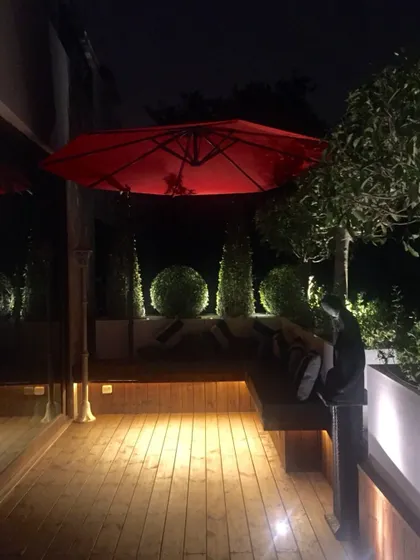 A balcony garden looks so inviting in the middle of the night. The wooden deck is softly lit, highlighting the seating area and topiaries, creating a quiet space for personal time.