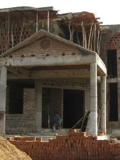 The front view of a building under construction, highlighting the formation of a gabled portico and arched window openings. This shows how architectural details are incorporated early in the structural phase.