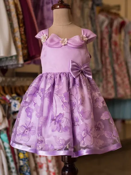 A lovely lavender creation fit for a princess. This dress features a sheer floral overlay on the skirt and delicate floral appliqués on the bodice, making it a whimsical choice for any special event.
