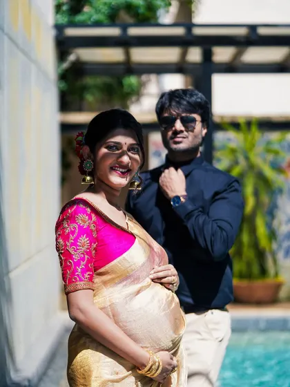 A lovely portrait of the expecting couple by the water. The focus is on the mother's happy smile and the protective presence of her partner.
