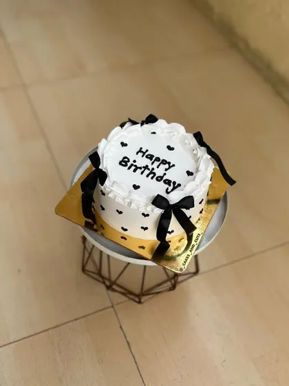 An overhead view of the black and white vintage cake with "Happy Birthday" written in the center.