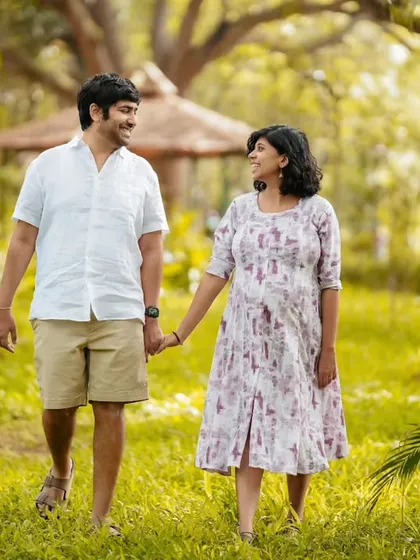 A happy, candid moment as a couple walks hand-in-hand through a sunlit park. Their smiles show the joy and excitement of this special time.