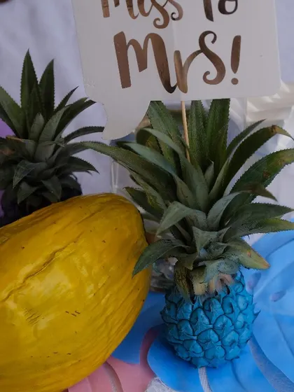 For a tropical or bohemian-themed bridal shower, I use fun decor elements like these painted pineapples and coconuts. The "Miss to Mrs" sign adds a celebratory touch to the decor.