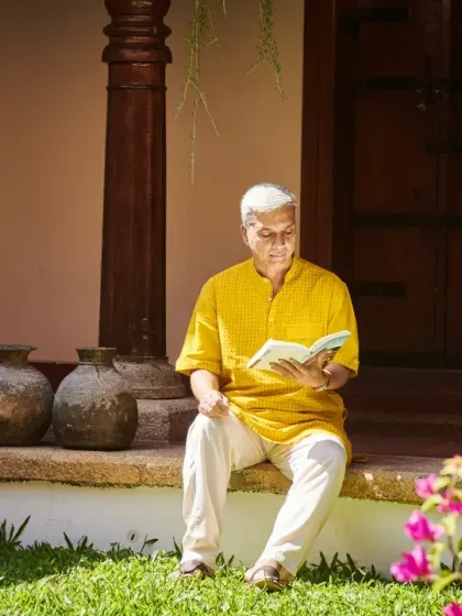 A guest enjoys a book on the veranda of a traditional nalukettu, with the sacred Tulasi plant nearby. Every corner of our campus invites you to slow down and reconnect.