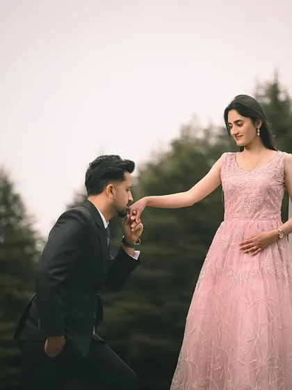 A classic gesture of romance, with him kneeling to kiss her hand against the soft, green backdrop of the forest. Her pink gown adds a touch of fairytale magic.