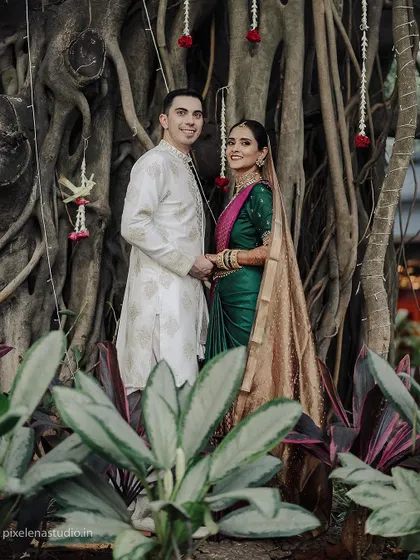 A classic portrait of a multicultural couple set against a backdrop of lush greenery and banyan tree roots. Their pose is elegant and timeless, celebrating their union.