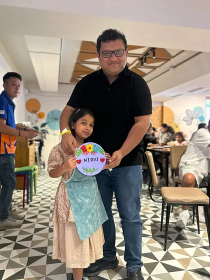 A proud dad with his daughter and her beautifully painted floral nameplate. It's a perfect Father's Day gift, made with love.