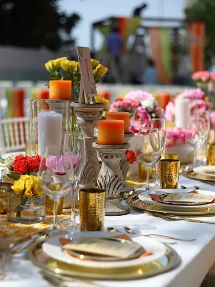 A vibrant and colourful table setting for a daytime event, with bright orange candles and multi-hued floral arrangements. This shows our versatility in creating different moods through decor.