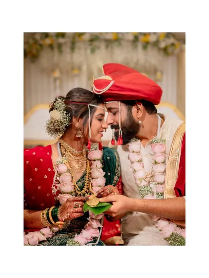 An intimate portrait of a Maharashtrian couple during their wedding ceremony, holding a betel leaf as part of the ritual.