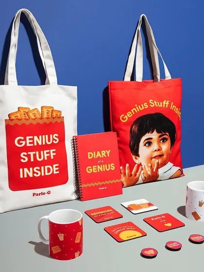 A group shot of the Parle-G merchandise, including tote bags, mugs, and coasters. The clean, color-blocked background aligns with the brand's iconic packaging and creates a strong, cohesive look.