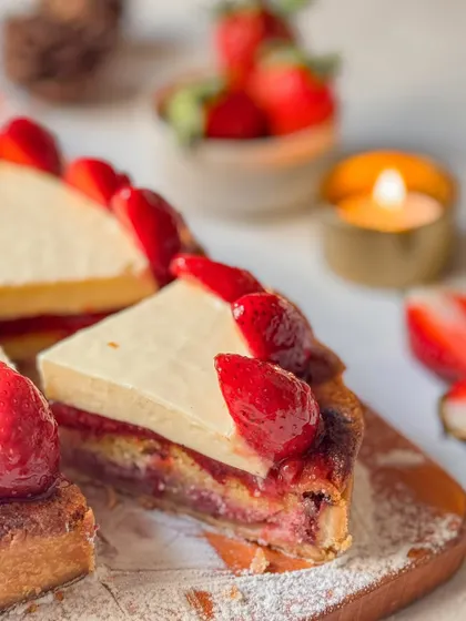 A slice of our Strawberry Tart, showing the layers of buttery crust, almond frangipane, and strawberry jam, all topped with fresh berries. It's a complex and satisfying dessert.
