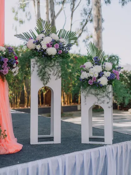 Modern white pedestals with beautiful floral arrangements, used to frame a stage or entrance.