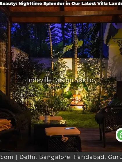 A cozy outdoor seating area under a pergola at night. The space is softly lit, highlighting the Buddha statue in the background and creating a perfect spot for quiet contemplation.