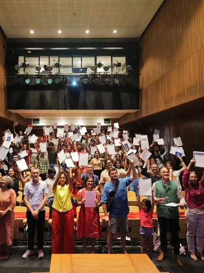 A packed auditorium of students proudly holding up their certificates after the "La Dictée pour Tous" event. Every participant is a winner in our inclusive and encouraging competitions.