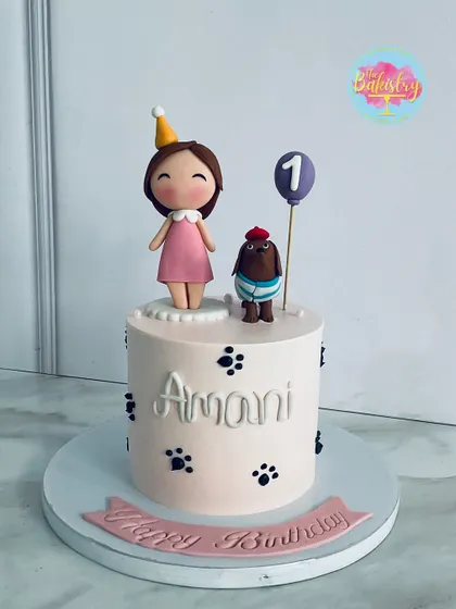 A whimsical cake for Amani's first birthday, featuring a cute girl, her dog, and paw prints.