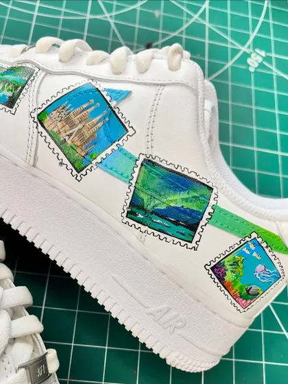 A close-up of the travel stamp sneakers, showing the detail on the Sagrada Familia and Northern Lights stamps.