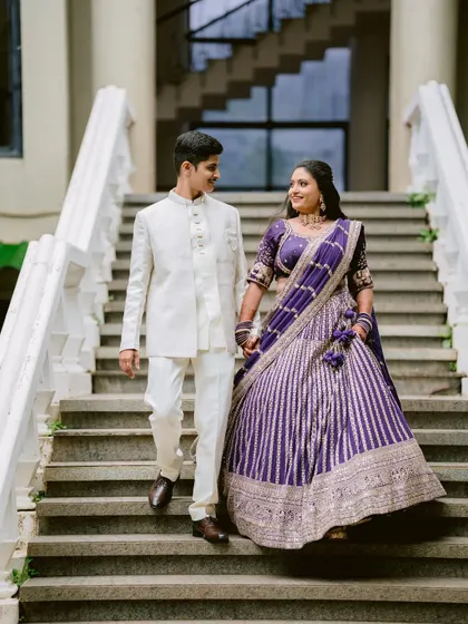 Apeksha and Rutwij descending the stairs hand-in-hand, a beautiful portrait from their engagement day.