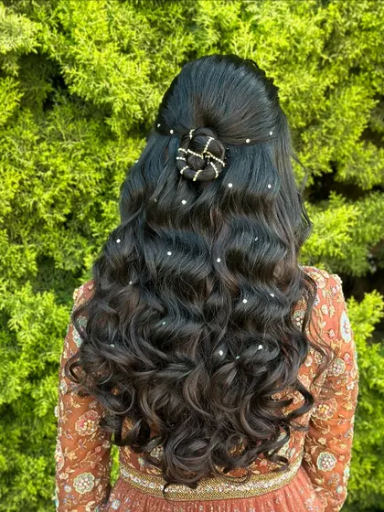 A classic half-up style with a braided bun and beautiful curls. The scattered pearls add a touch of magic to this romantic look.