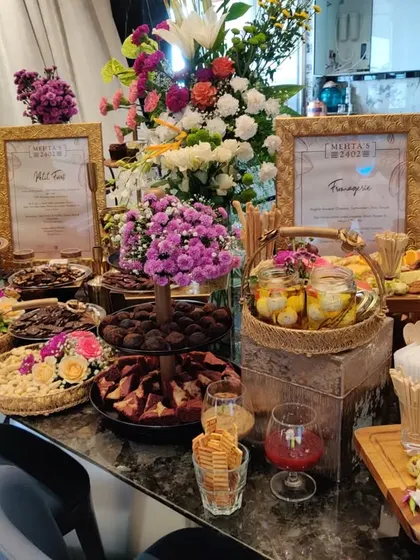 The full view of a decadent grazing table at a private evening celebration. Adorned with fresh flowers, the table features a curated selection of cheeses, desserts, and savoury bites to delight every guest.