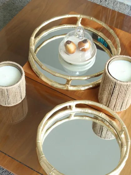 A pair of our round bamboo-style mirror trays, styled with candles and a cloche. They are perfect for creating a layered and sophisticated look on a coffee table or console.