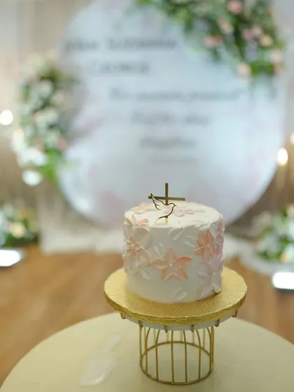 A closer look at the floral painted cake for a beautiful baptism. The pastel pink and peach tones are so soft and sweet, and the golden topper with the dove and cross adds a perfect finishing touch for the occasion.